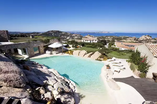 Piscina dal design bio con spiaggia, rocce e pareti degradanti