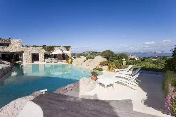 Piscina stile lago naturale con rocce e bagnasciuga