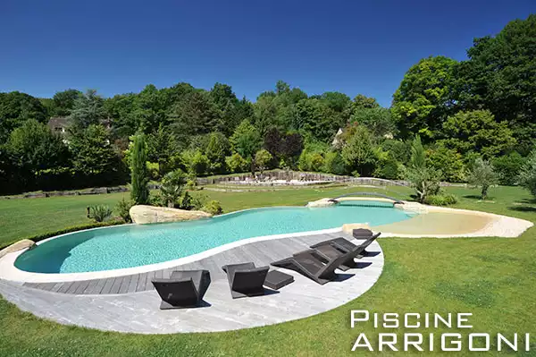 Piscina stile lago con superfici materiche e spiagge acqua bassa